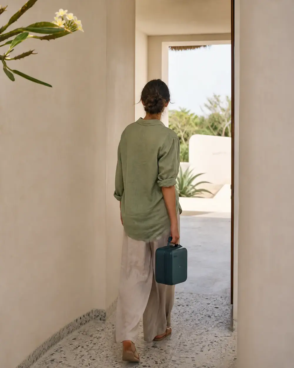 Funktion clinician arriving through a villa doorway on a home visit, seen from behind